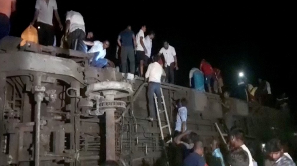 Civis sobem em cima de vagão de trem que descarrilou em Balasore, na Índia — Foto: ANI/Reuters TV via REUTERS