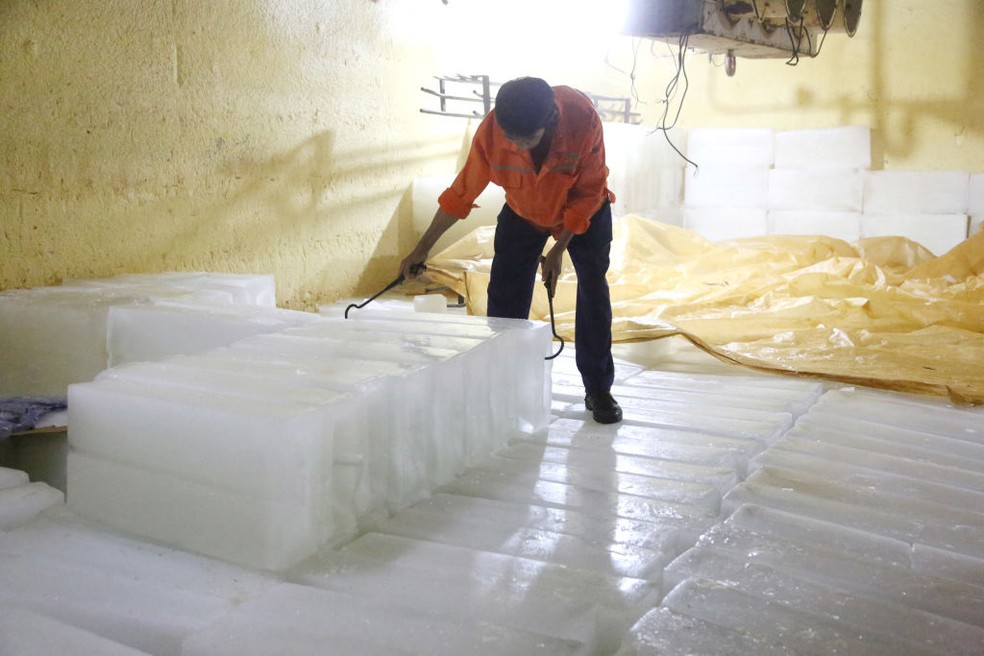 Um trabalhador processa cubos de gelo em uma fábrica de processamento de cubos de gelo na cidade de Lianyungang, província de Jiangsu, leste da China, em 14 de julho — Foto: Getty Images